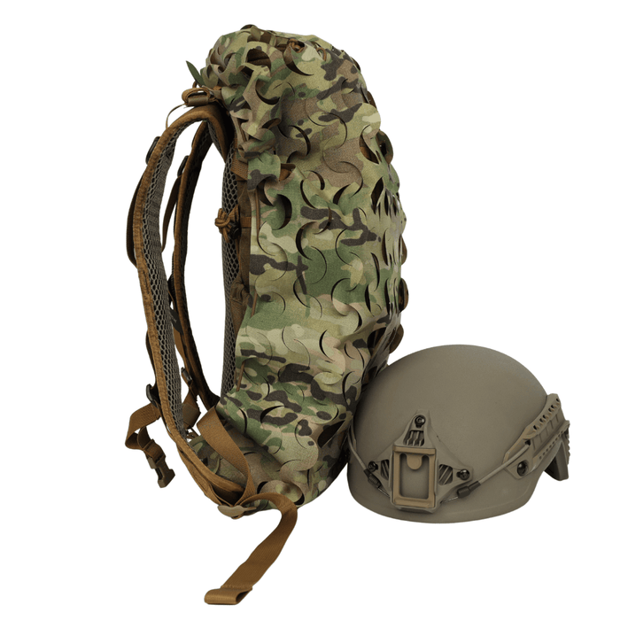 The OPE Gear Backpack Scrim - Camouflage Pack Cover by OPE Gear is shown standing upright beside a matte tan military helmet with mounting hardware, both set against a plain white background.