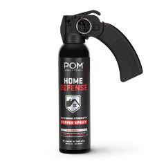 A black canister labeled "POM Home Defense 9.2oz Pepper Spray" by POM, featuring a large pistol-grip handle and safety pin. The label displays a warning and states it is made in the USA.