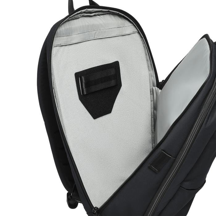 A close-up of a partially unzipped Vertx Any Day Backpack by Vertx shows its light gray interior, black Velcro strap, and a padded compartment compatible with ballistic panels.