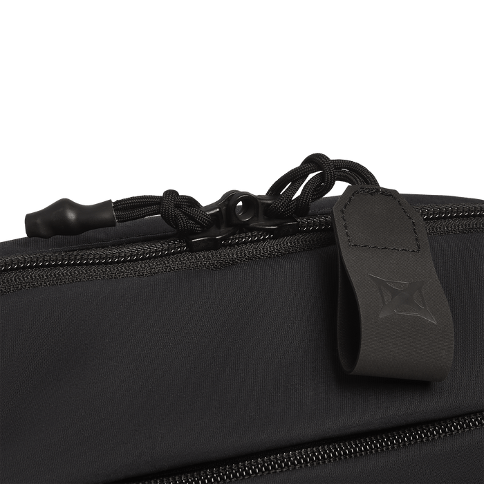 Close-up of a black zipper on the Vertx Everyday Fanny Pack+ by Vertx, showing a looped zipper pull with stitched geometric logo and knotted cord—designed as a ballistic-panel compatible CCW waist pack.