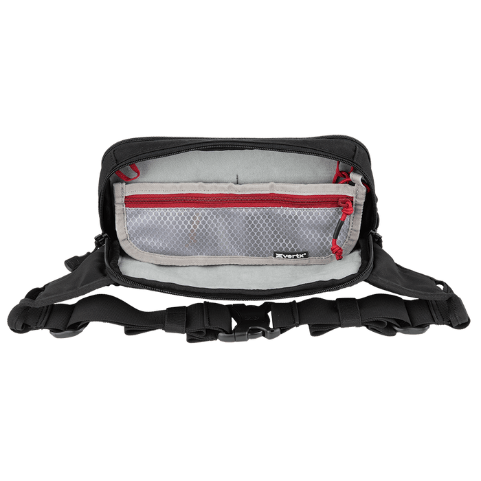 A black Vertx SOCP Tactical Fanny Pack from Vertx, with its top compartment open, displays an interior lined with light gray fabric. Inside, there's a mesh zippered pocket accented with red trim. The bag features multiple external straps, buckles, padded areas, and space for a body armor insert.